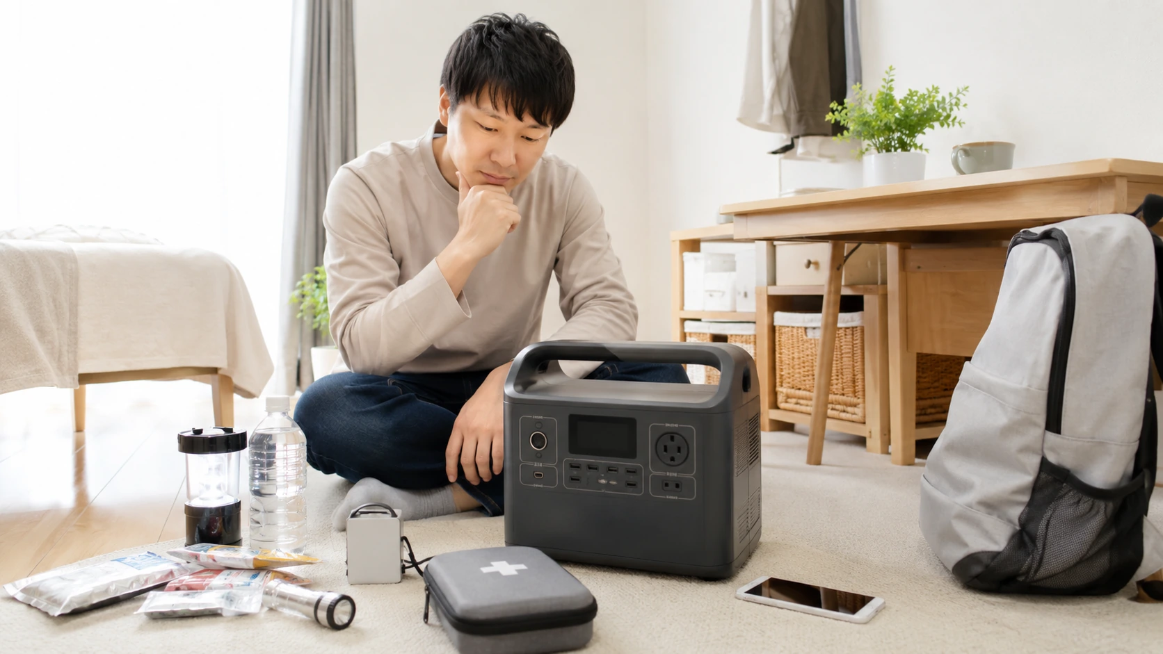 一人暮らしの部屋でポータブル電源の容量や出力を確認している様子